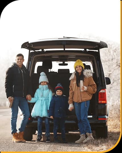 Family of four in winter gear behind van